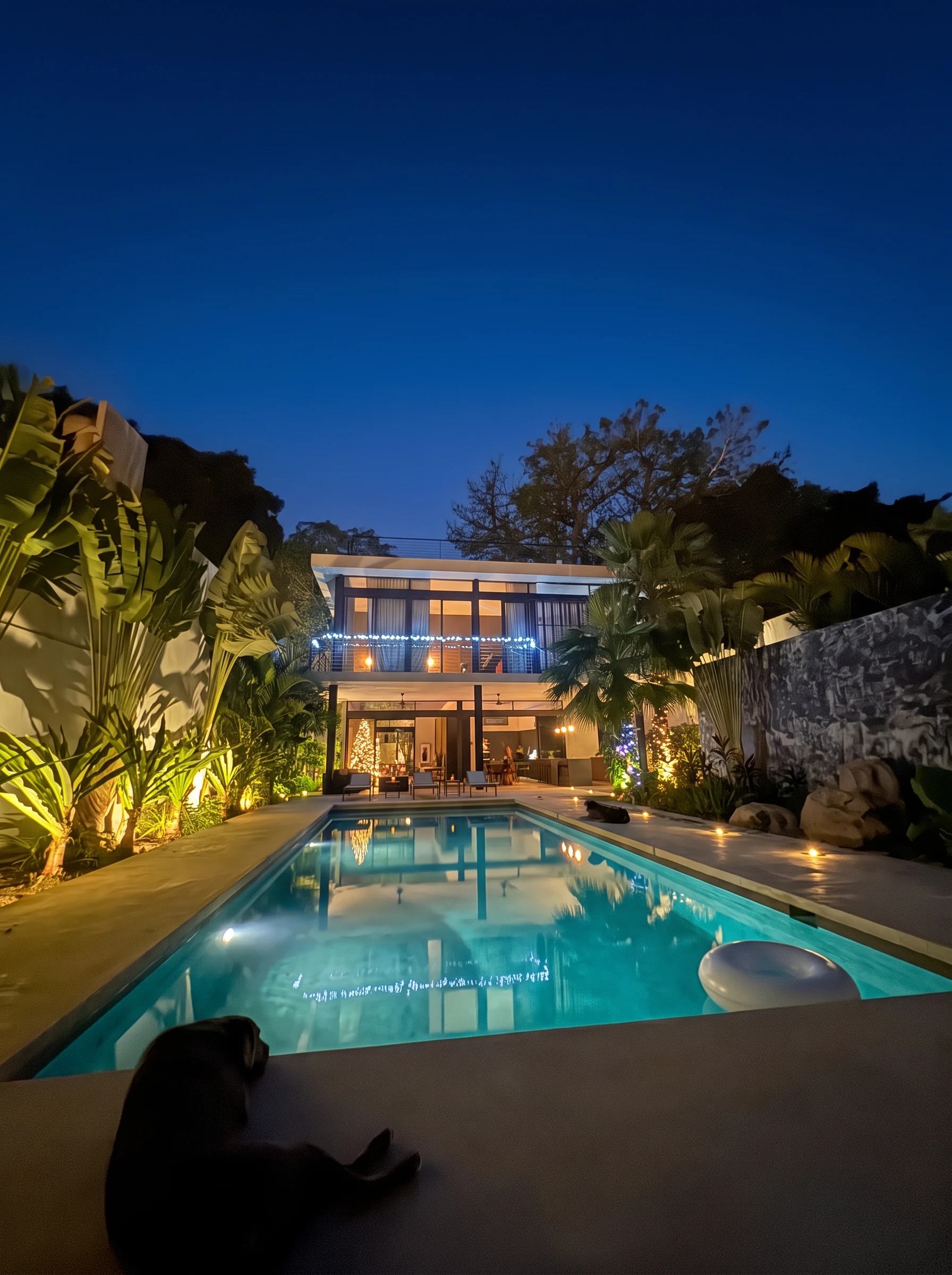 The pool at CASA AMADA at night, with both lit floors of the house beyond the garden